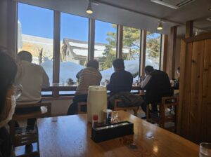 喜一のお店中、大きい窓に面した座席でラーメン食べてるところ